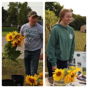 Andy holds sunflowers, Josie stands at the sale table