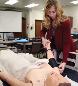 Holly Boylan administers a blood pressure cuff to a medical mannequin