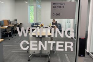 glass door with the words "writing center C-203" on it. The room is in the back ground of the photo.