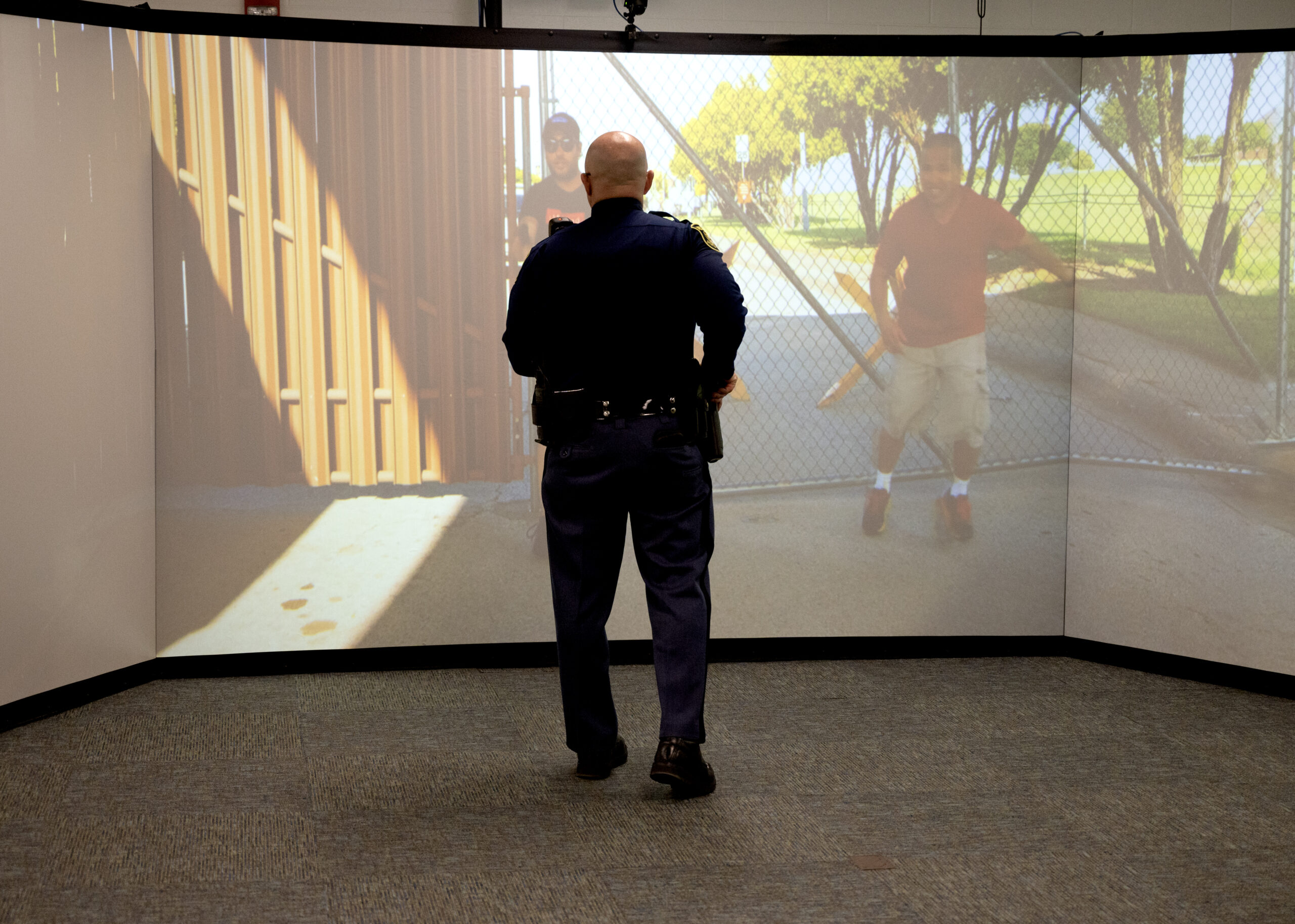 man with fake gun stands in front of large screen